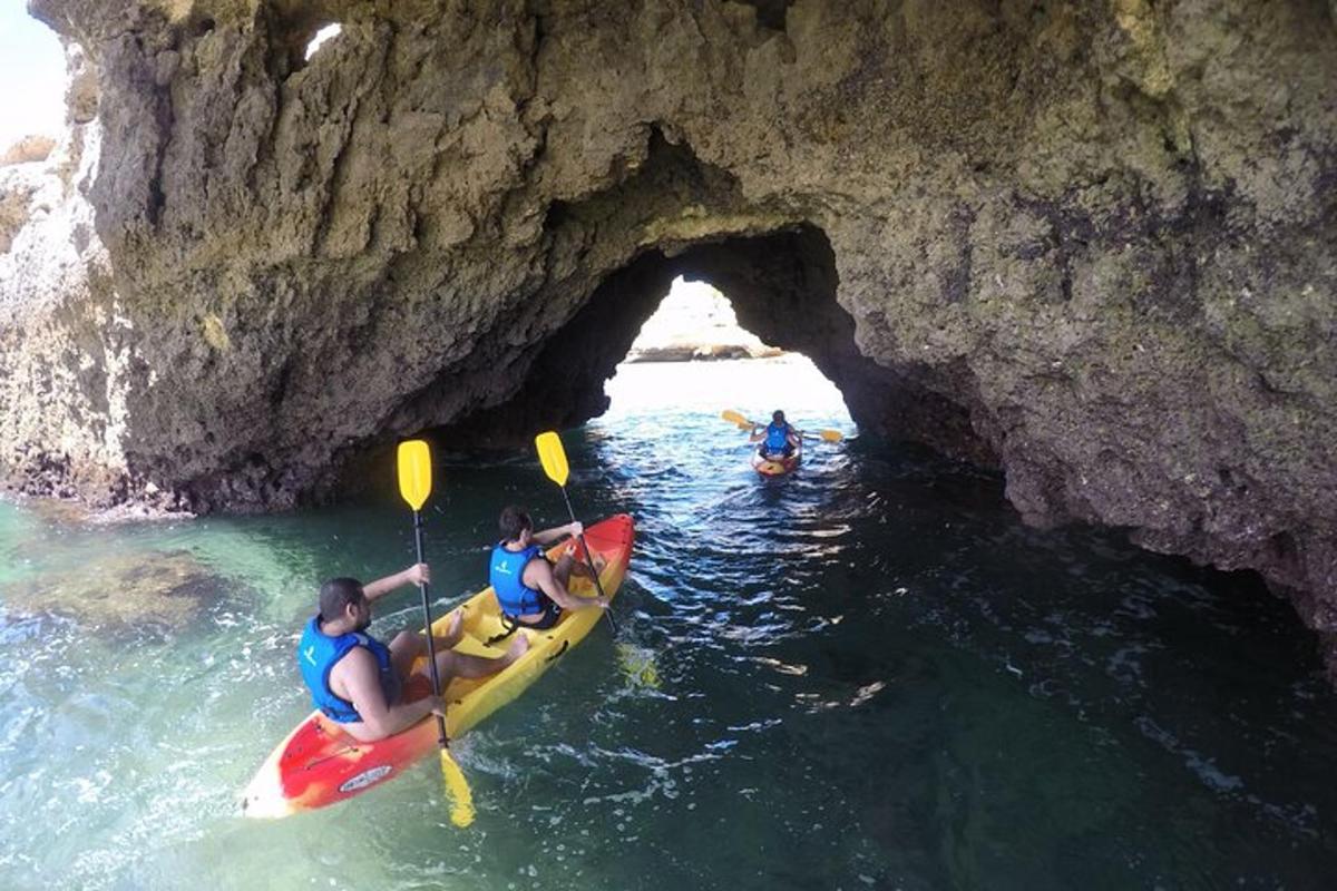 um grupo de pessoas em caiaques em frente a uma caverna