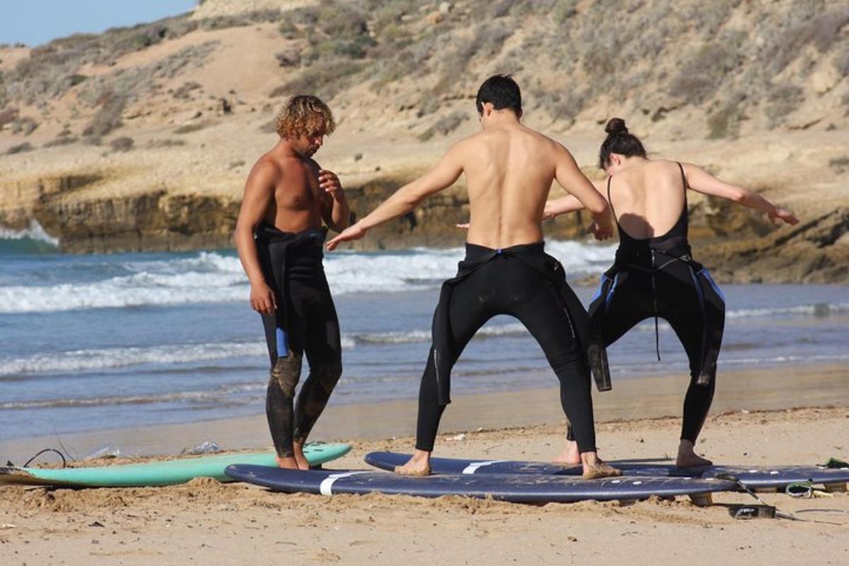 three men standing on surfboards on the beach
