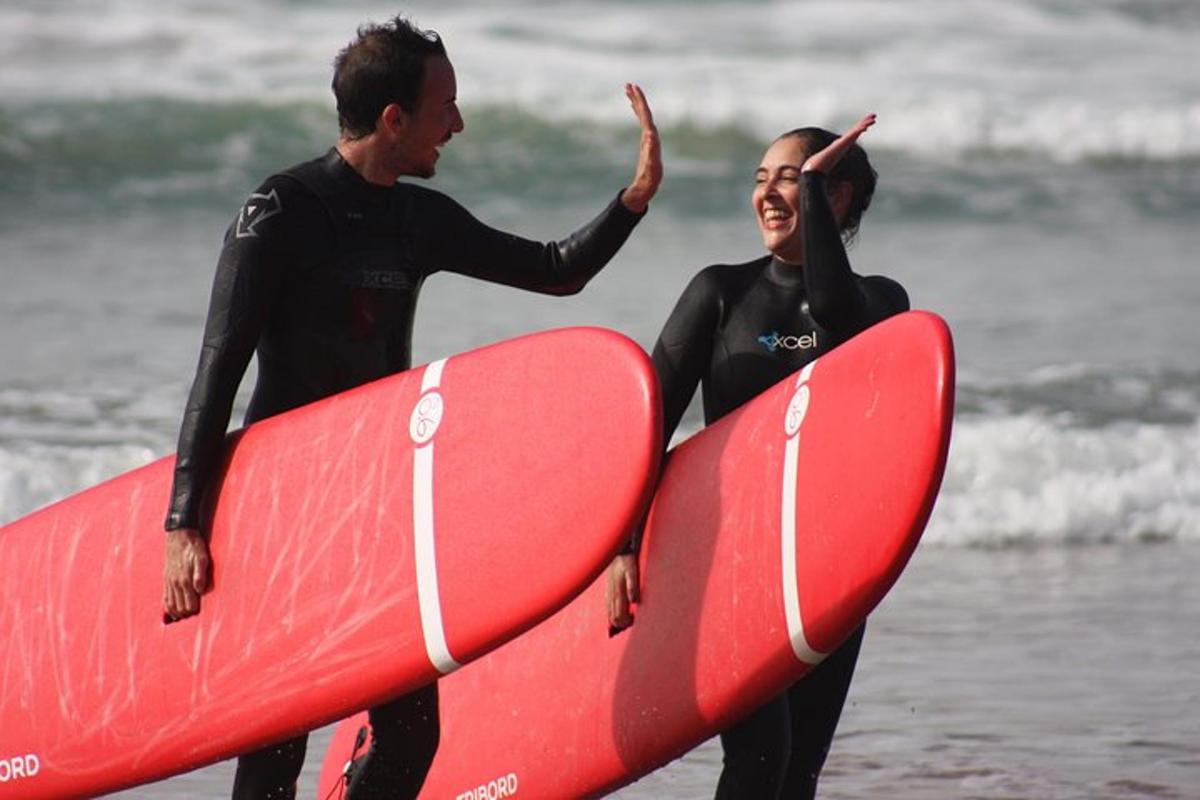 a man and a woman holding a surfboard on the beach