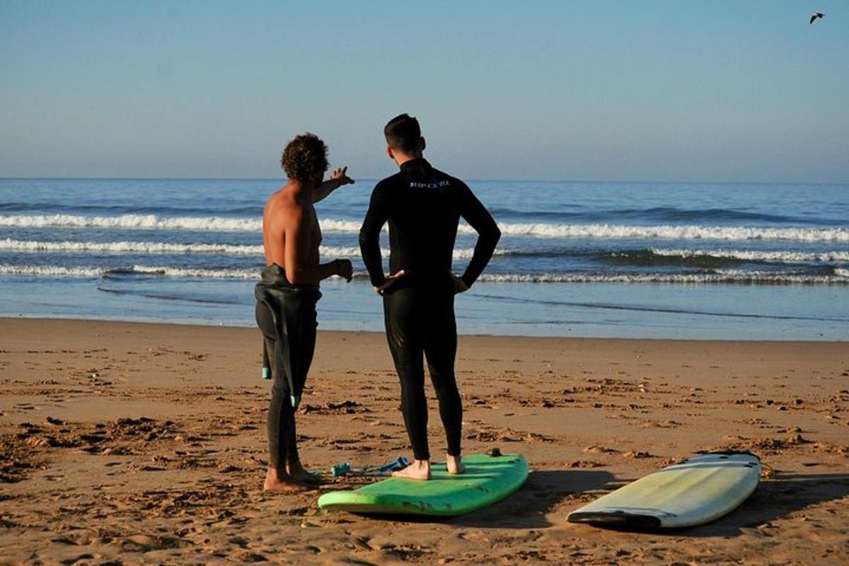two men standing on the beach with surfboards on the beach