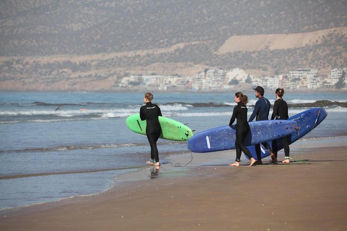 a group of people walking on the beach with surfboards