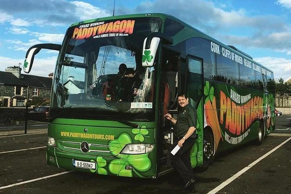 a man standing in the doorway of a green bus