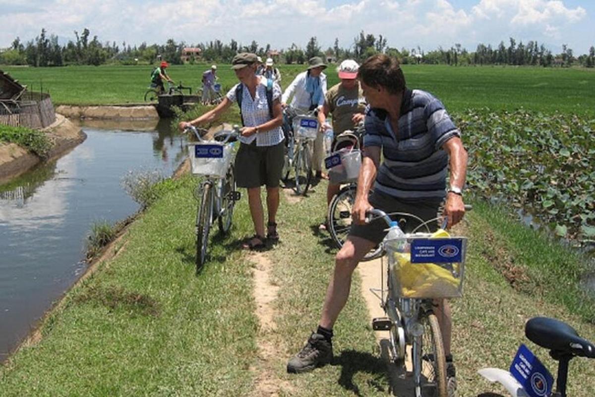 eine Gruppe von Menschen, die mit dem Fahrrad an einem Fluss entlang fahren