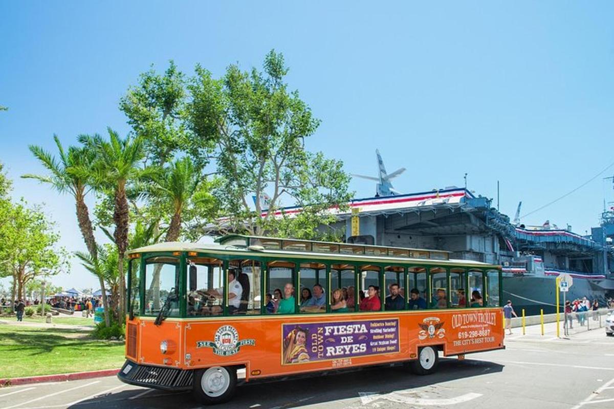an orange trolley filled with people driving down a street