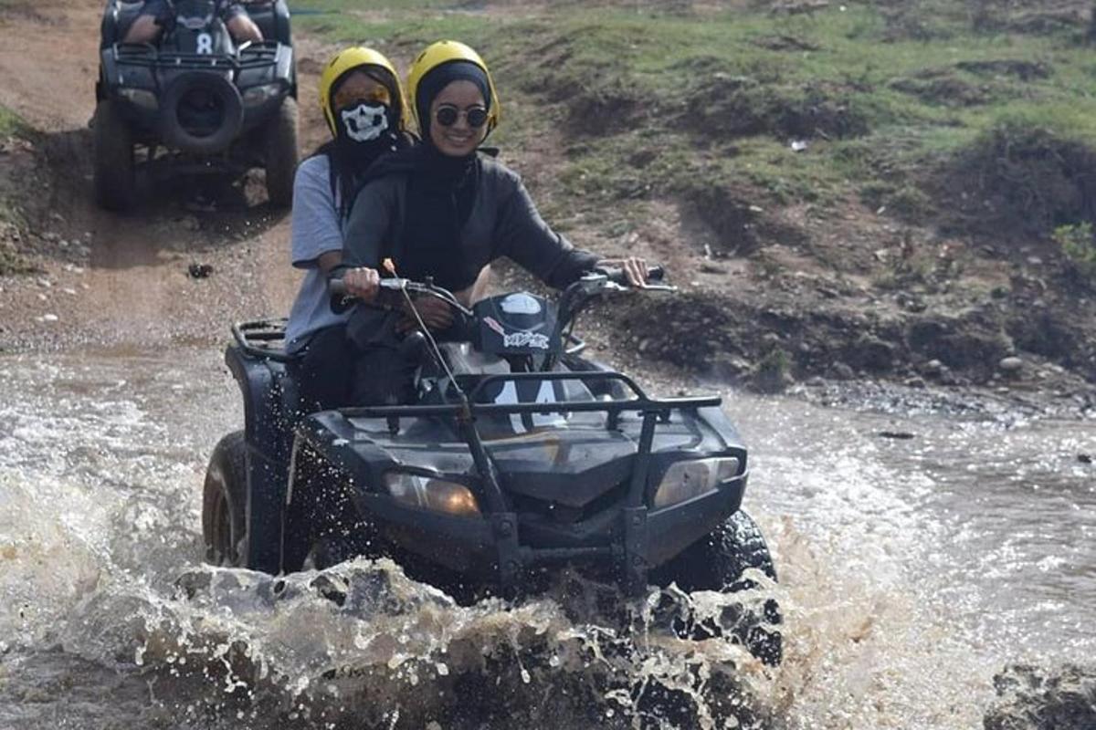 two people riding on a four wheeler through the water