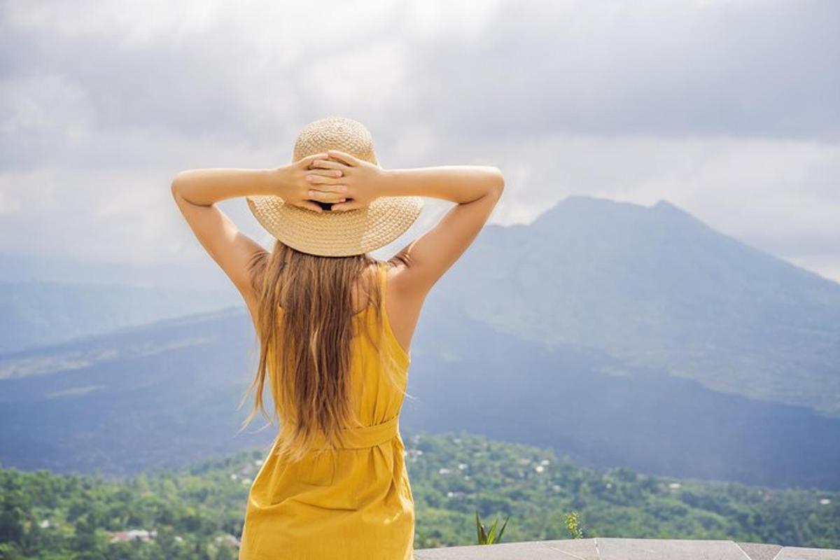 uma mulher usando um chapéu de palha olhando para uma montanha