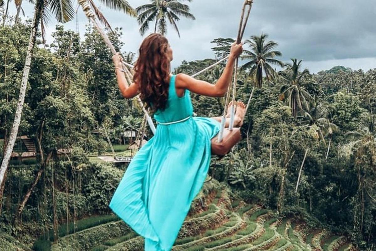 una donna in un vestito blu che si dondola su un'altalena di corda