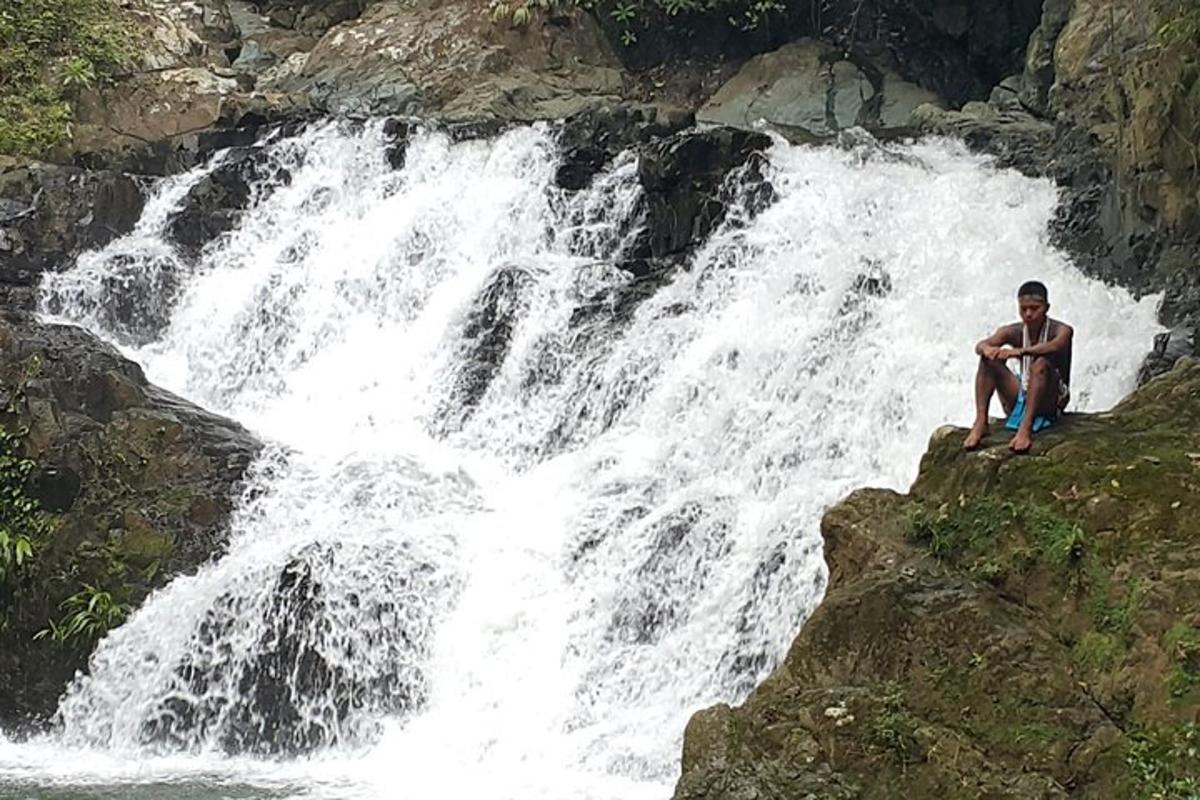 un uomo seduto su una roccia accanto a una cascata