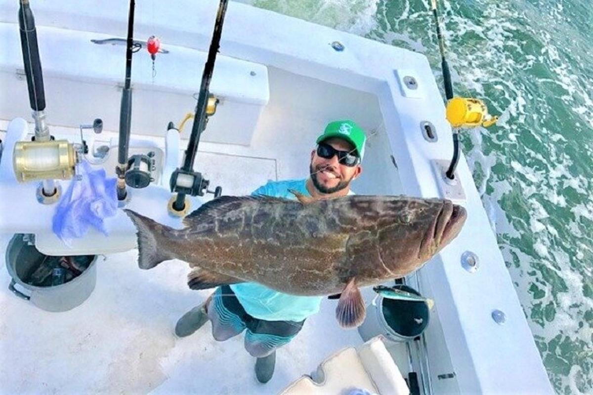 a man holding a large fish on a boat