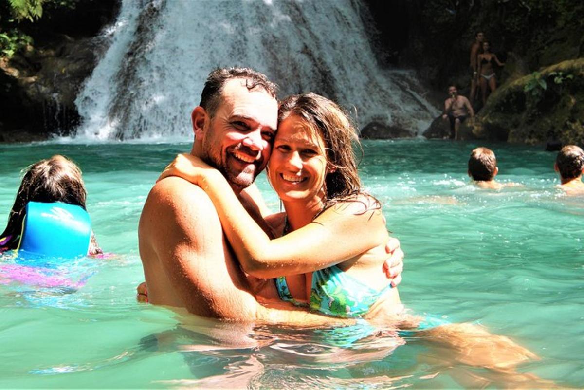 a man and woman in the water near a waterfall
