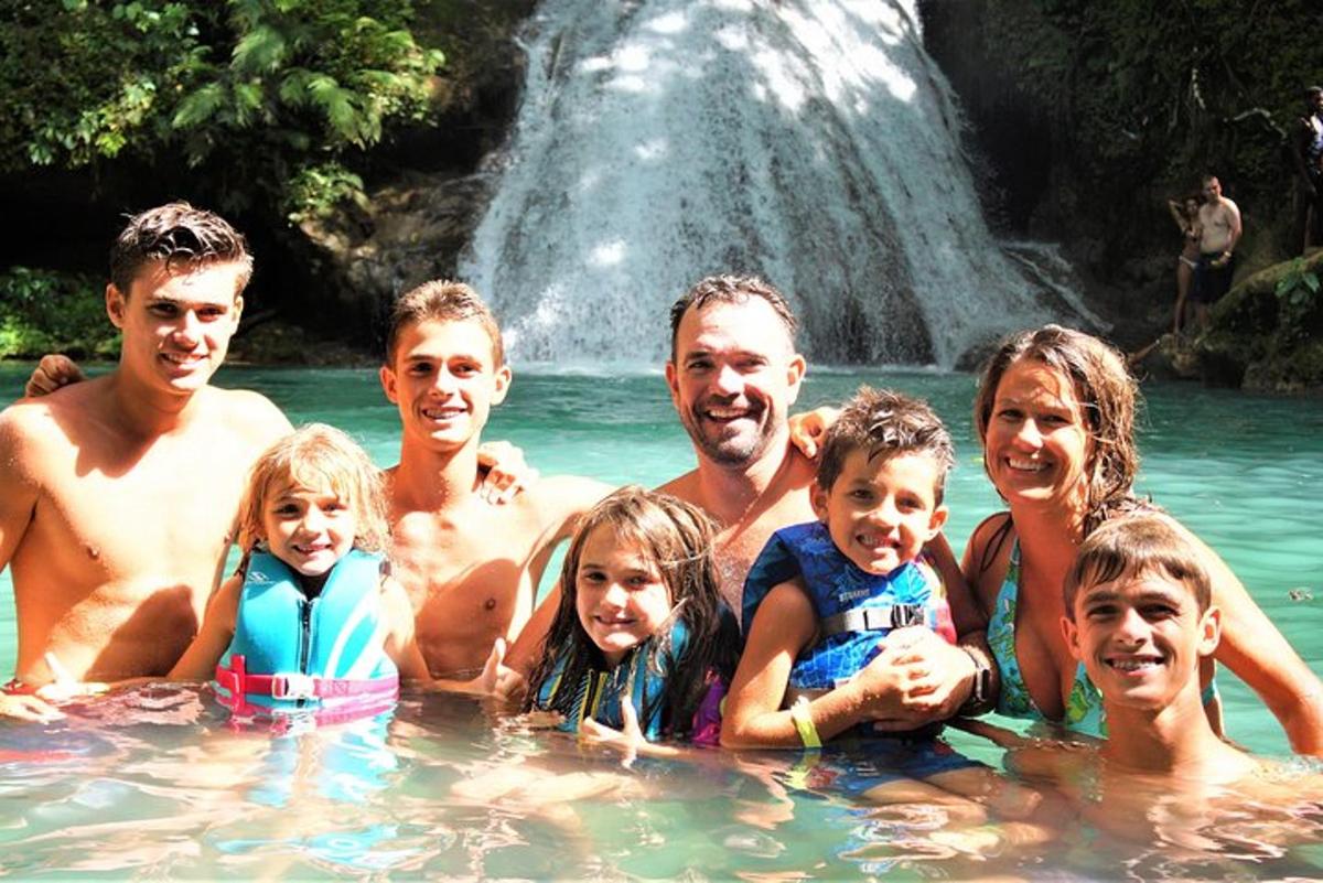a group of people in the water in front of a waterfall