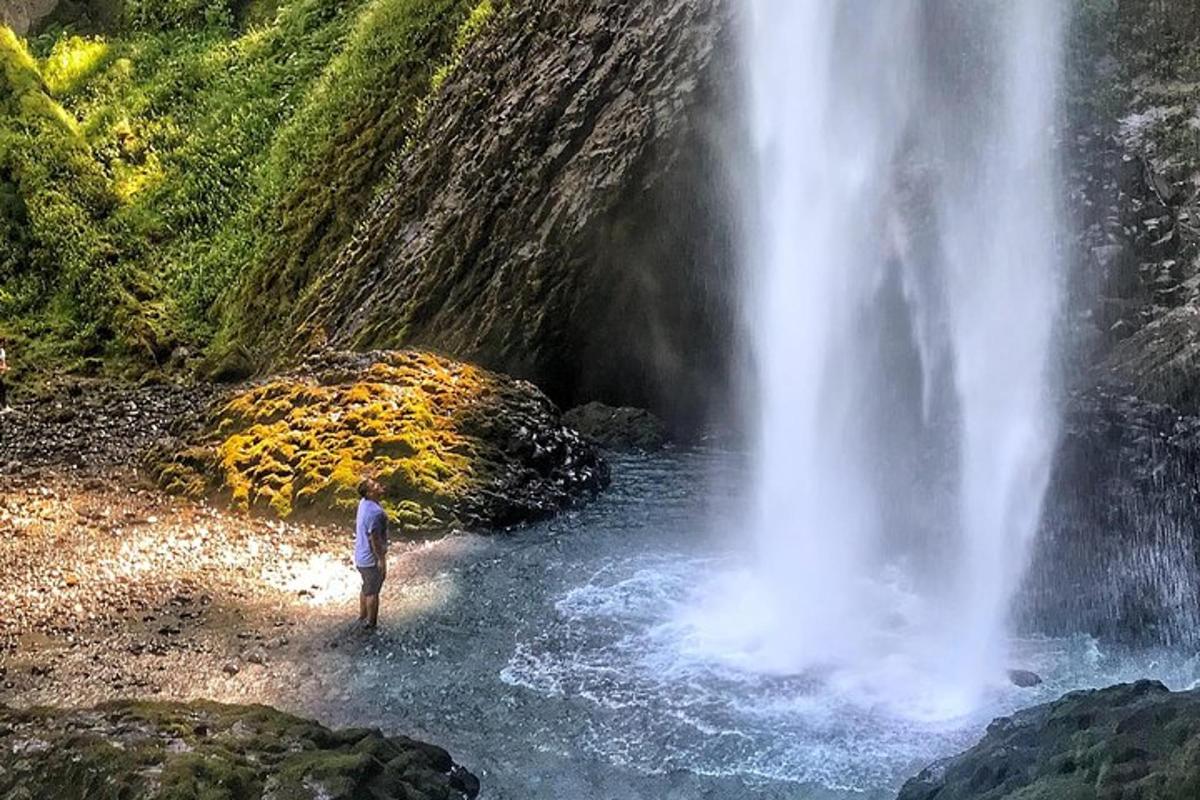 a man standing in the water next to a waterfall