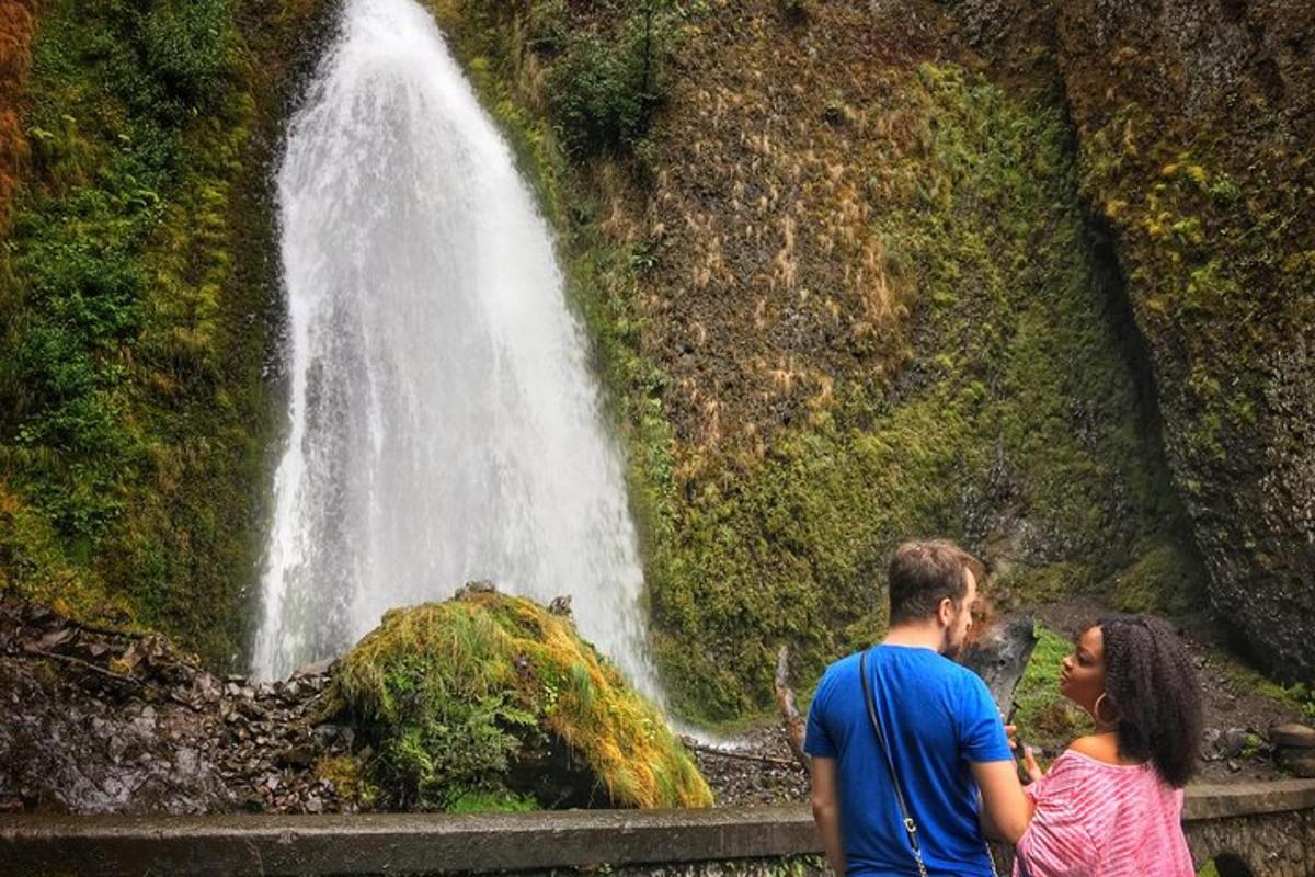 a man and woman standing in front of a waterfall