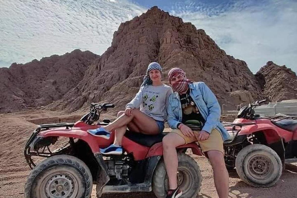 dua orang duduk di atas ATV di padang pasir