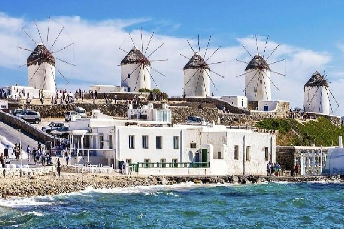 a group of windmills on a hill next to the water