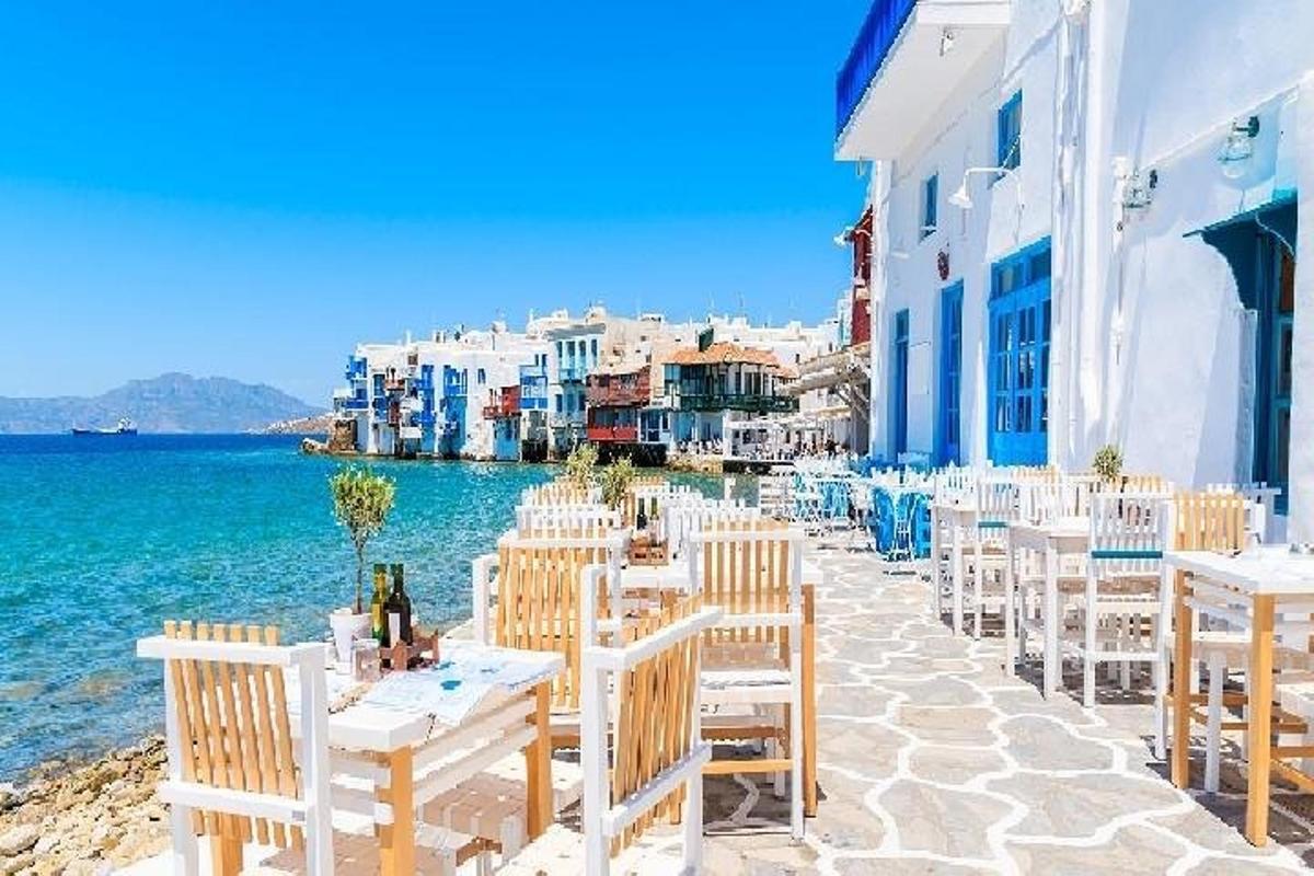a row of tables and chairs next to the water