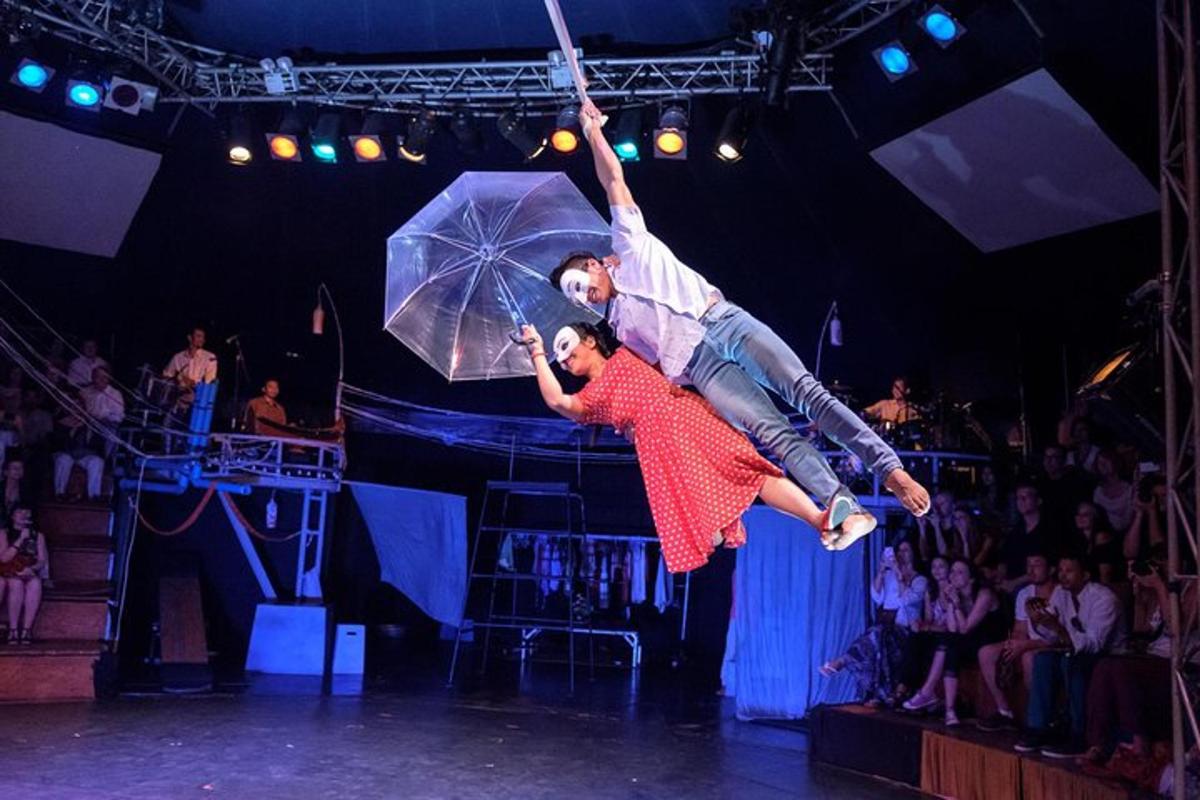 two people are performing on a stage with an umbrella