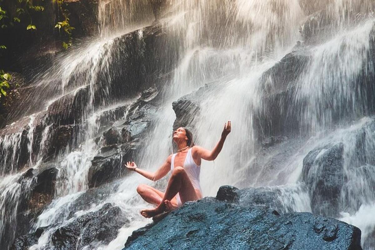 a woman sitting on a rock in front of a waterfall