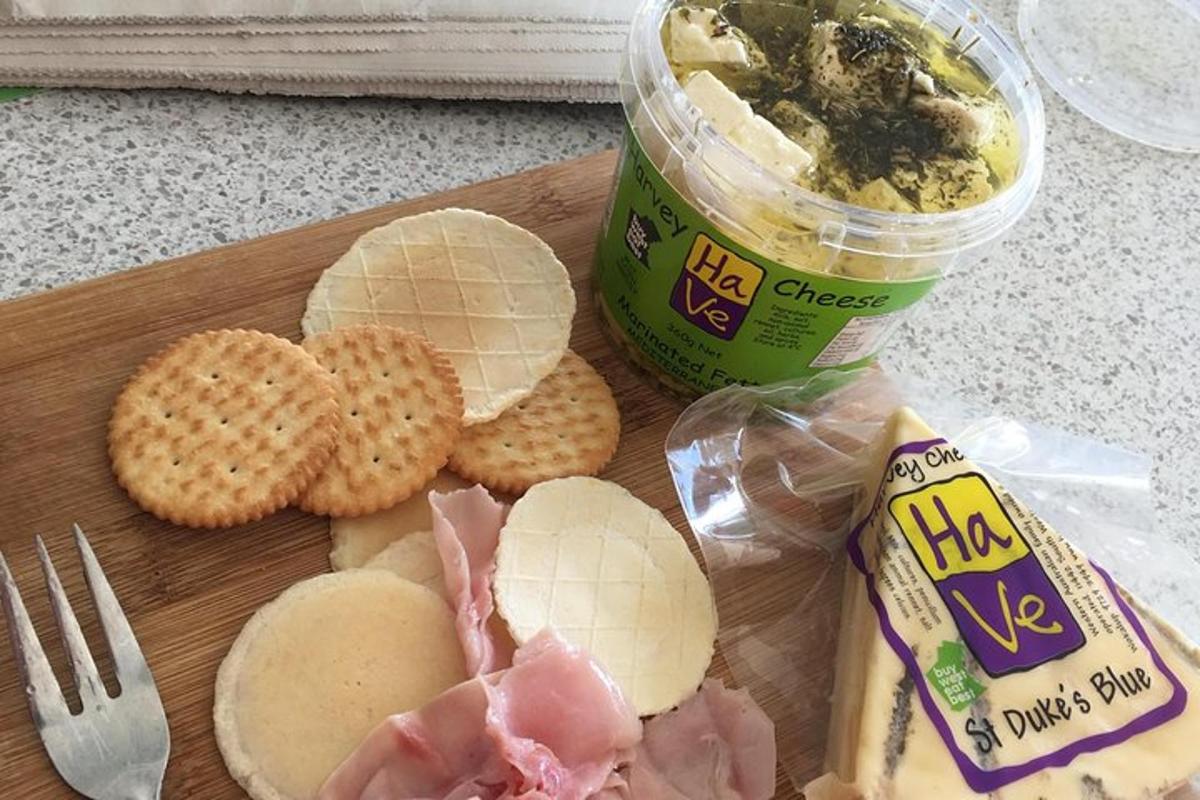 a cutting board with a sandwich and a container of dip