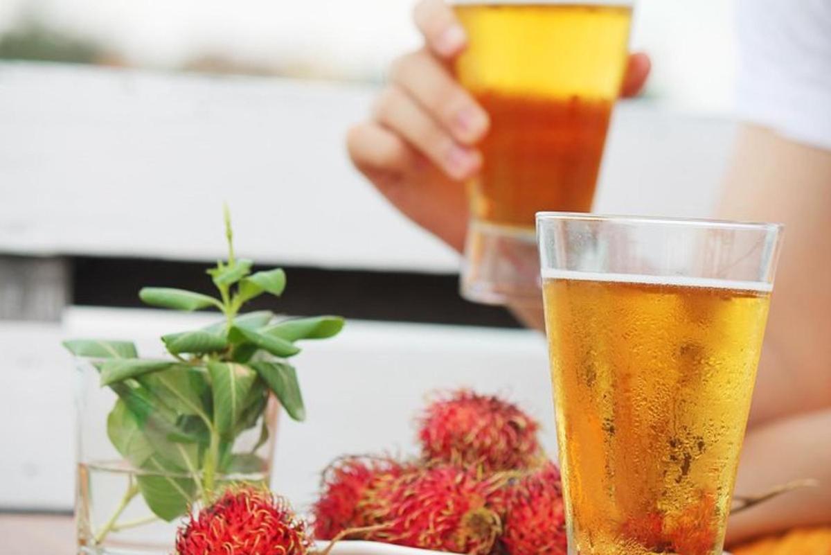 cilvēks tur glāzi alus un zemenes