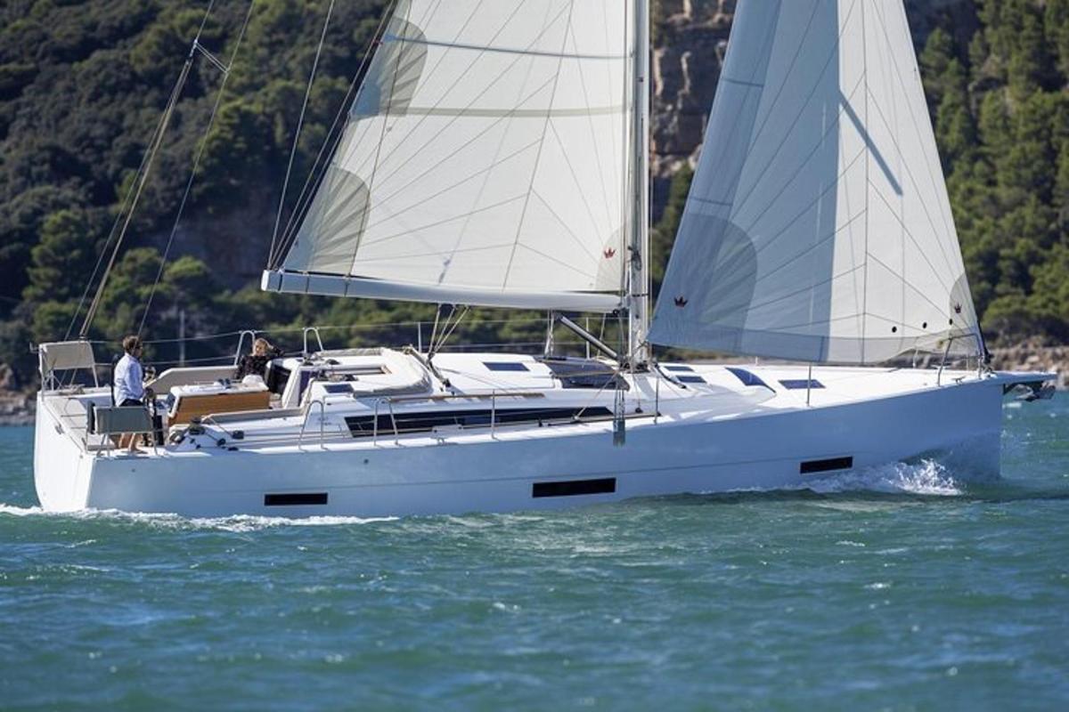 una barca a vela bianca con due persone a bordo in acqua