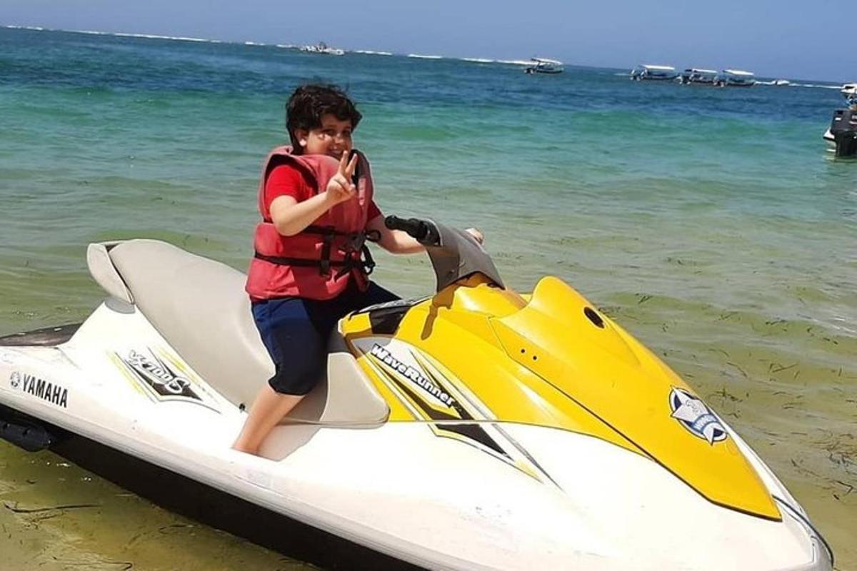 صبي صغير يركب دراجة مائية على الشاطئ