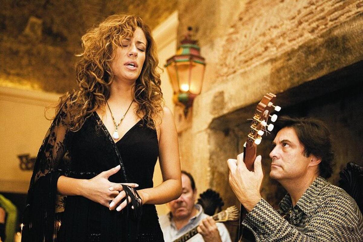 Una mujer parada junto a un hombre tocando una guitarra
