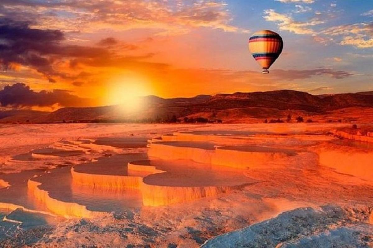 a hot air balloon flying over the desert at sunset
