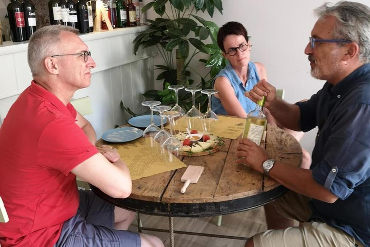 two men and a woman sitting at a table with wine glasses