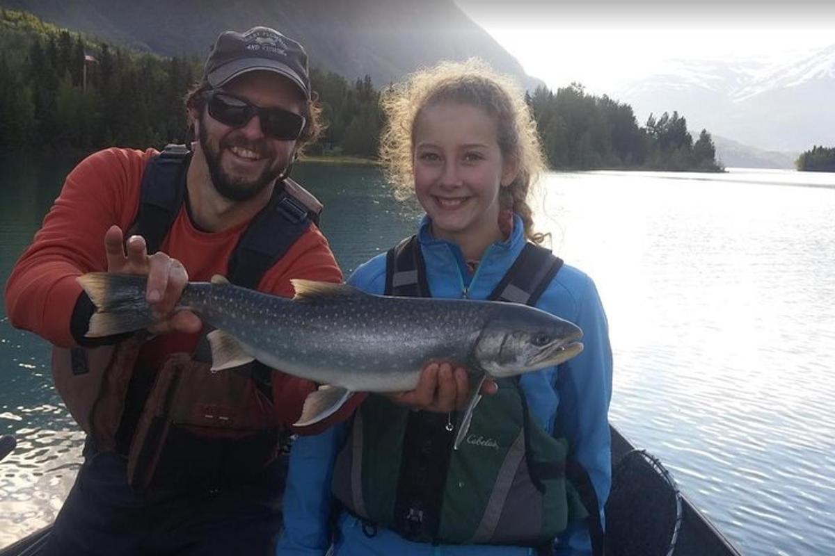 a man and a girl holding a fish in a boat