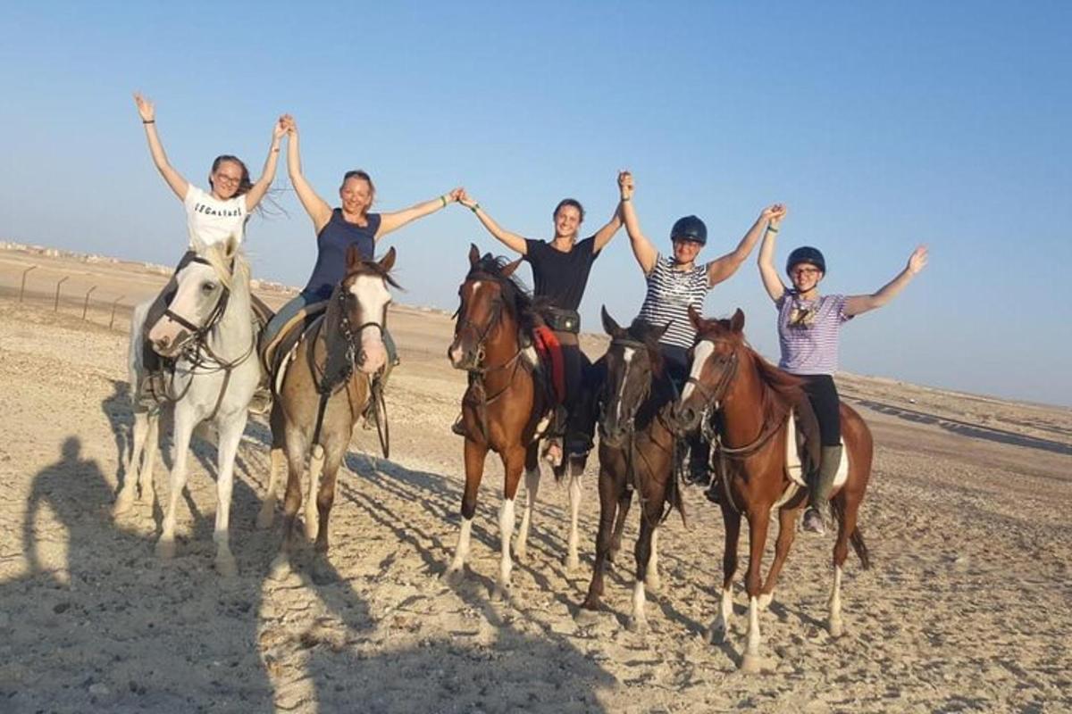 a group of people riding horses on the beach