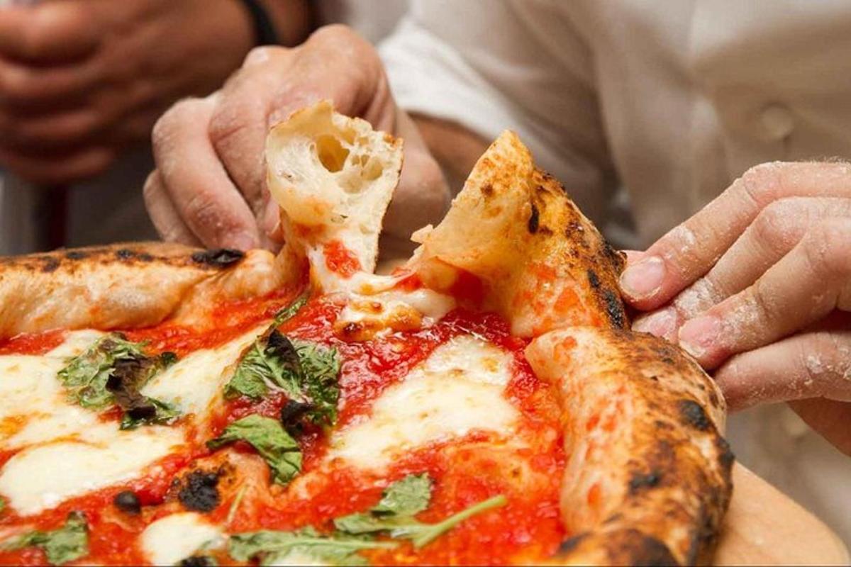 una persona sta prendendo una fetta di pizza