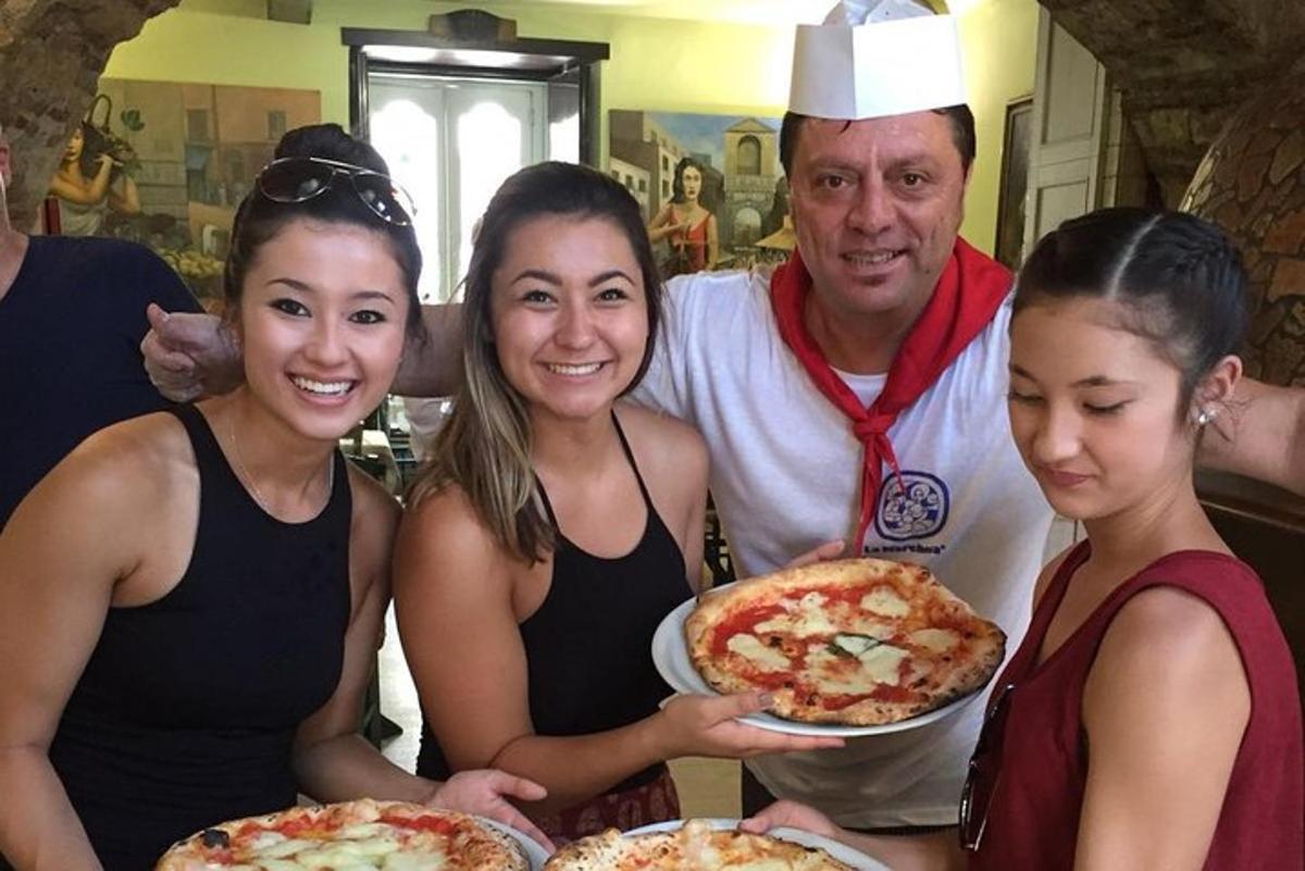 un uomo e tre donne che tengono in mano una pizza