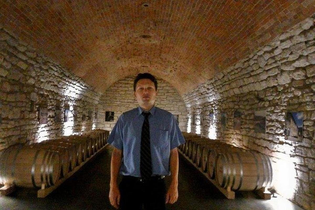 a man in a tie standing in a wine cellar