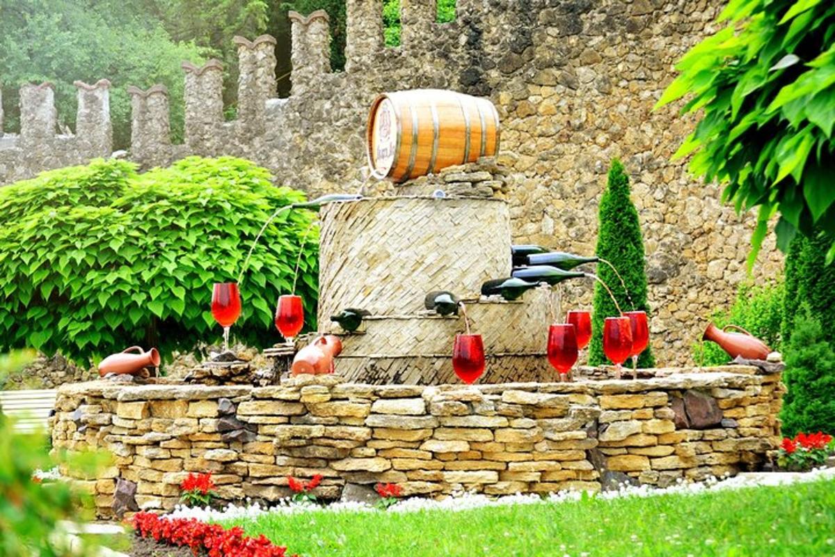 a water fountain with a barrel and red wine glasses