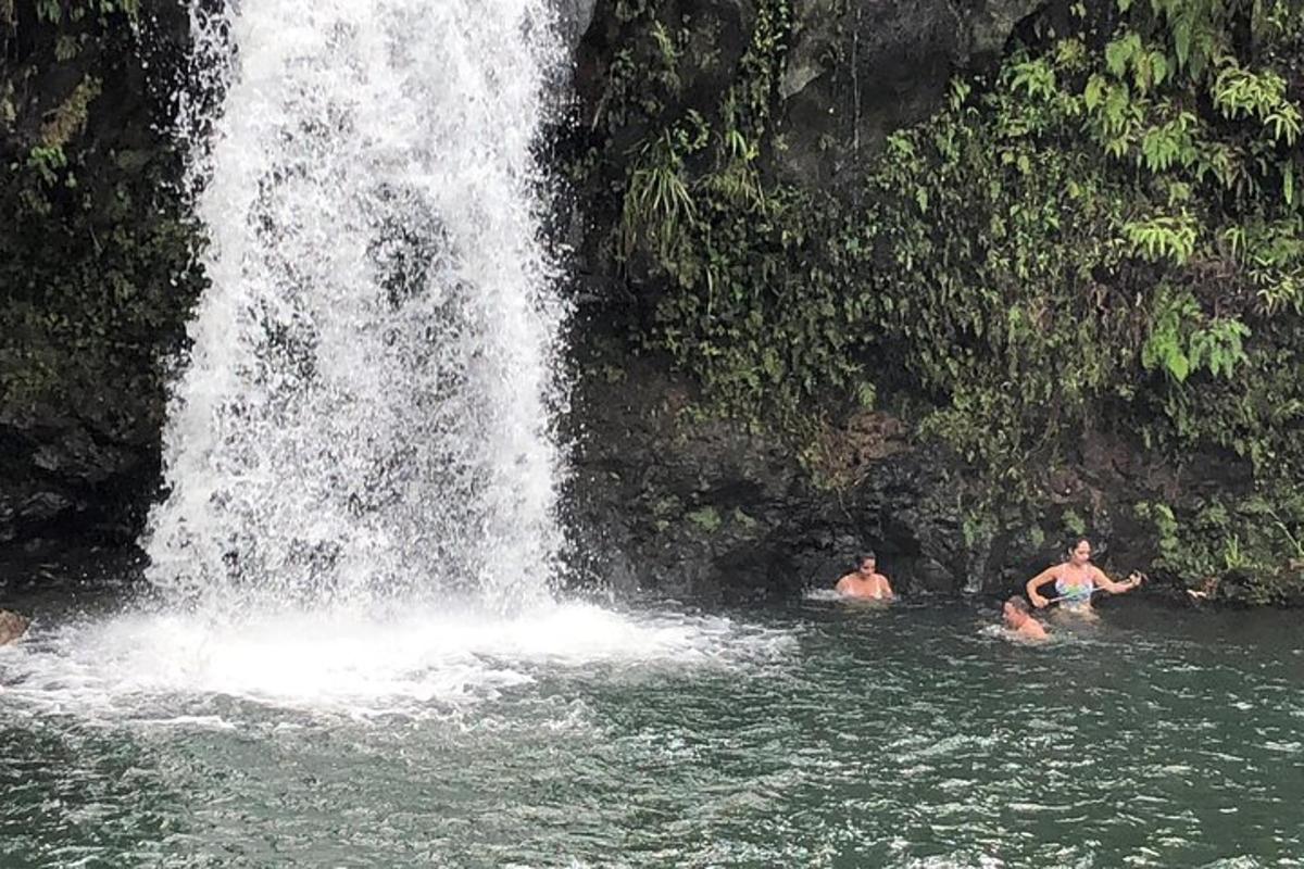 two people swimming in the water near a waterfall