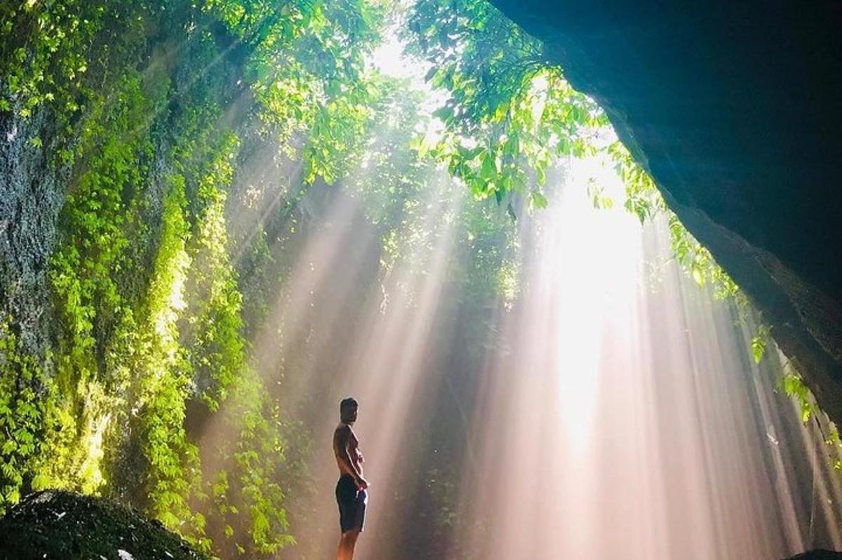 một người đàn ông đứng giữa hang động với những tia nắng mặt trời