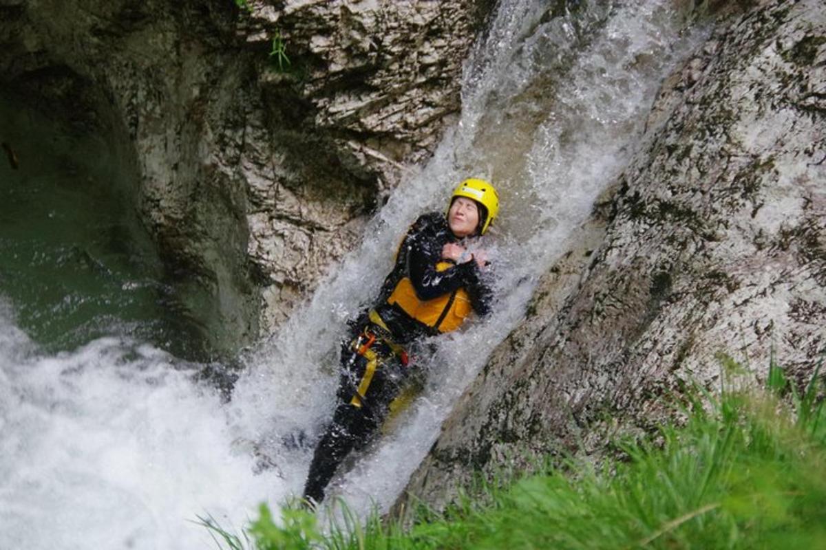 un uomo con un casco giallo in piedi in una cascata