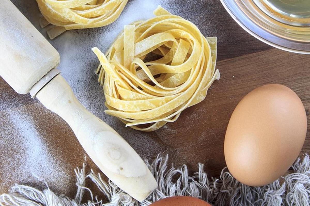 uma mesa com macarrão, um ovo e uma faca