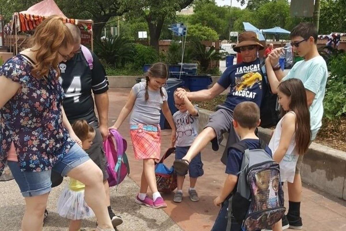 un gruppo di persone in piedi attorno a un gruppo di bambini