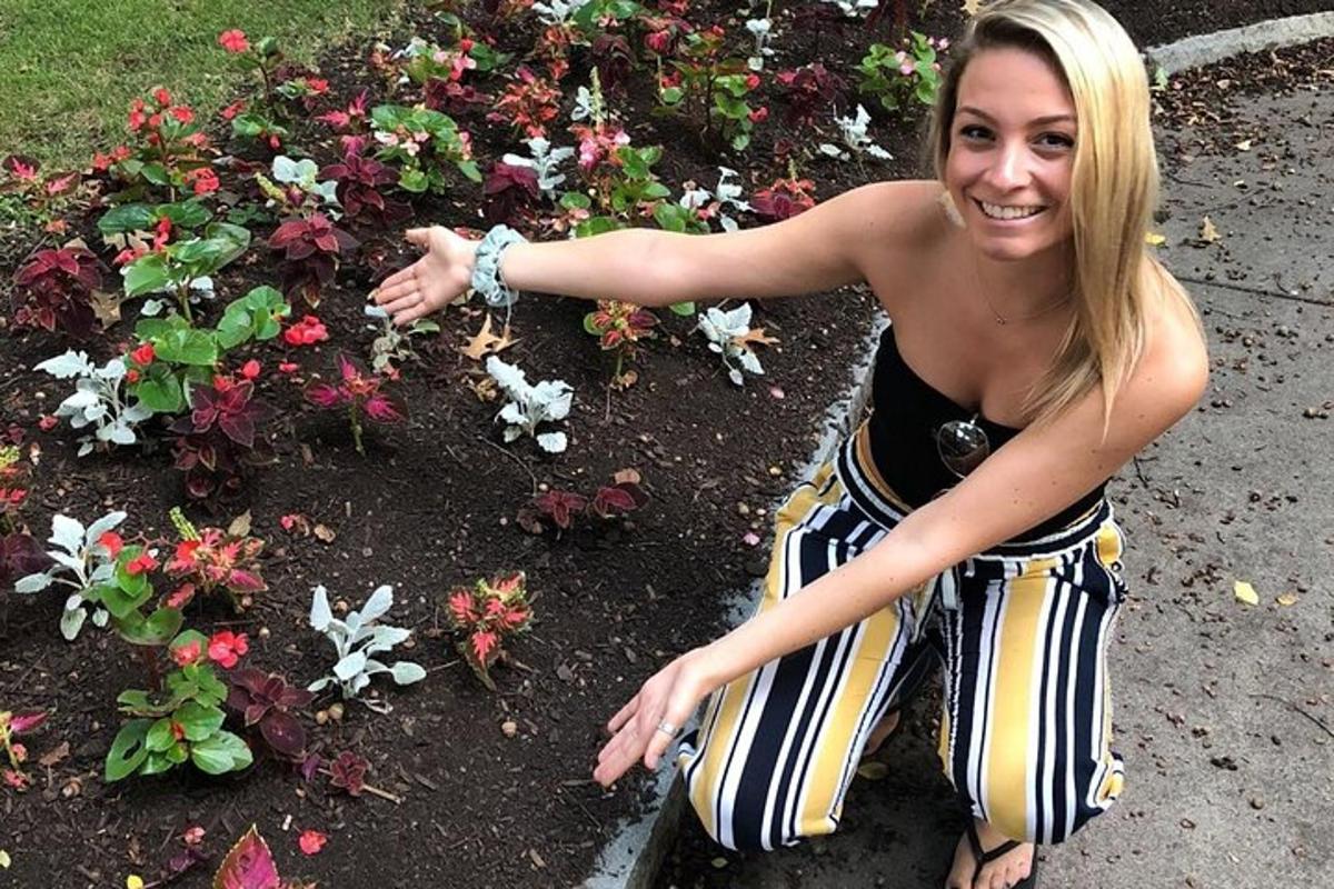 Una mujer parada frente a un macizo de flores