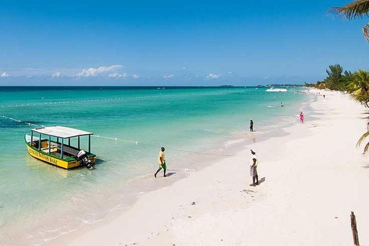 a yellow boat on a beach with people on it