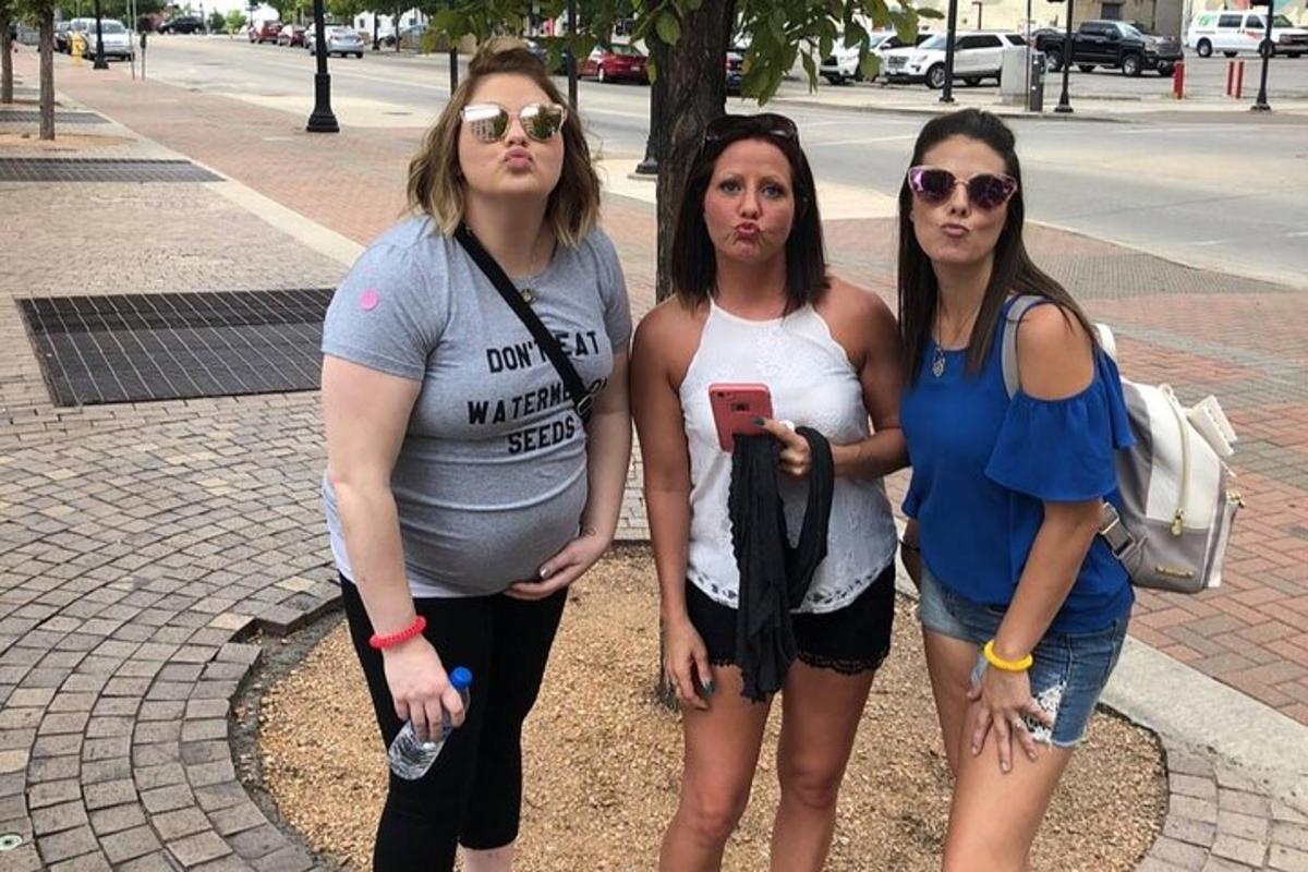 Un grupo de tres mujeres de pie junto a una calle.