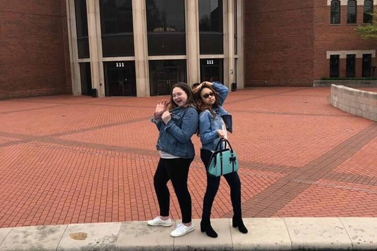 two girls standing on a sidewalk in front of a building