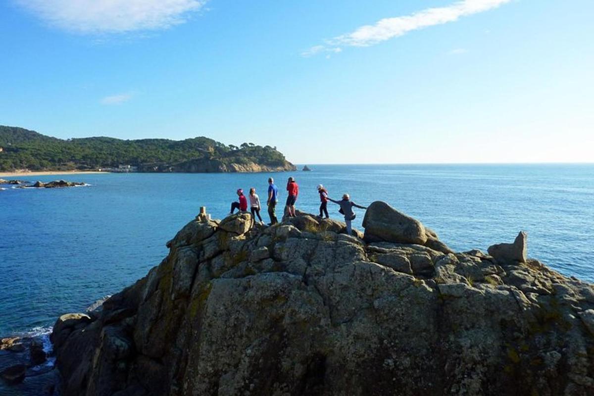 Un grupo de personas de pie sobre una formación rocosa en el océano.