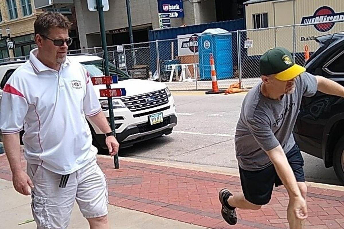 dva muži jdoucí po ulici s autem