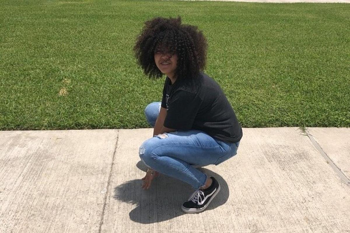 Žena sedí na skateboardu na chodníku