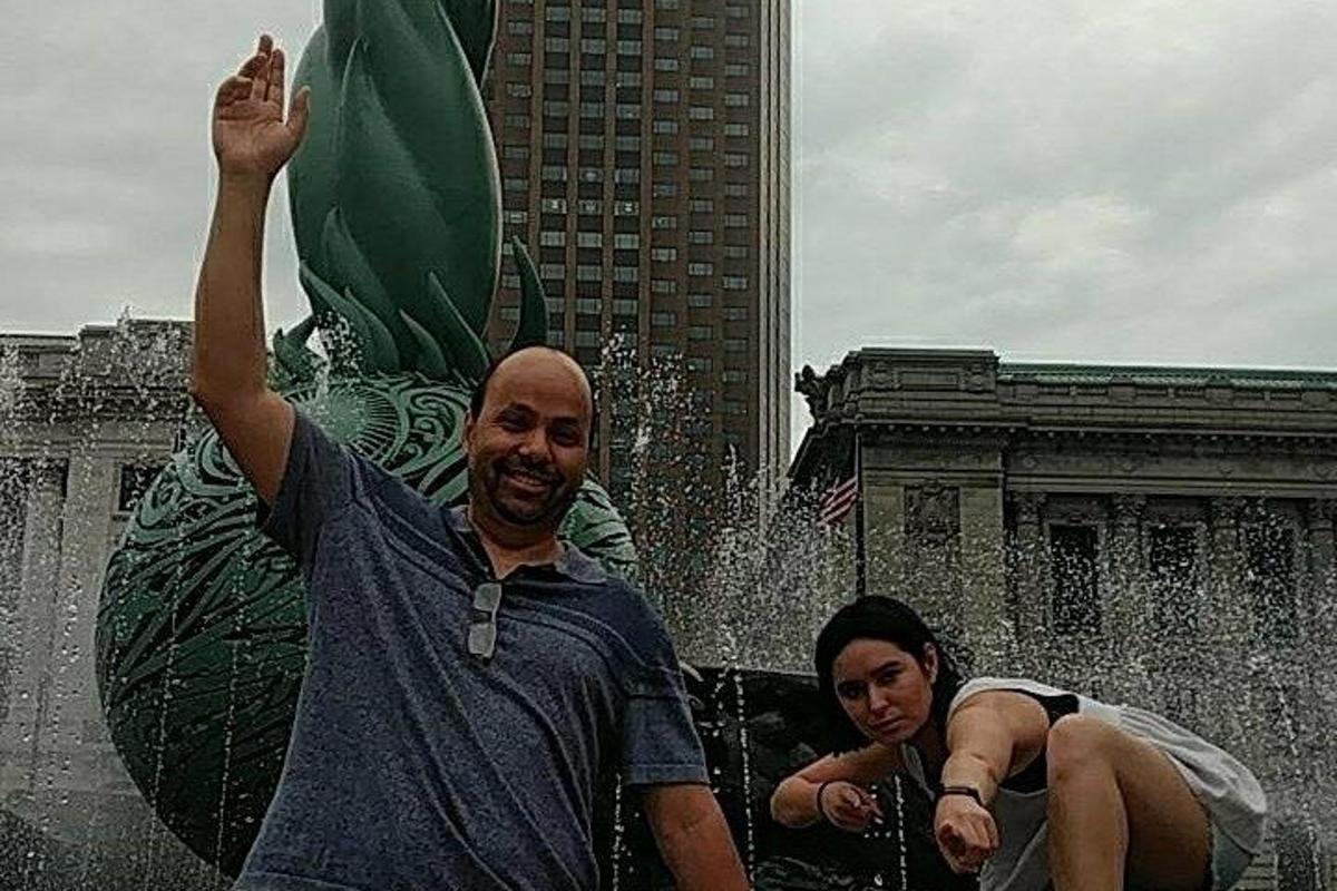 一名男子站在喷泉前，举起双手