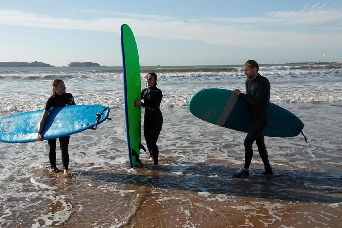 three people standing on the beach with their surfboards