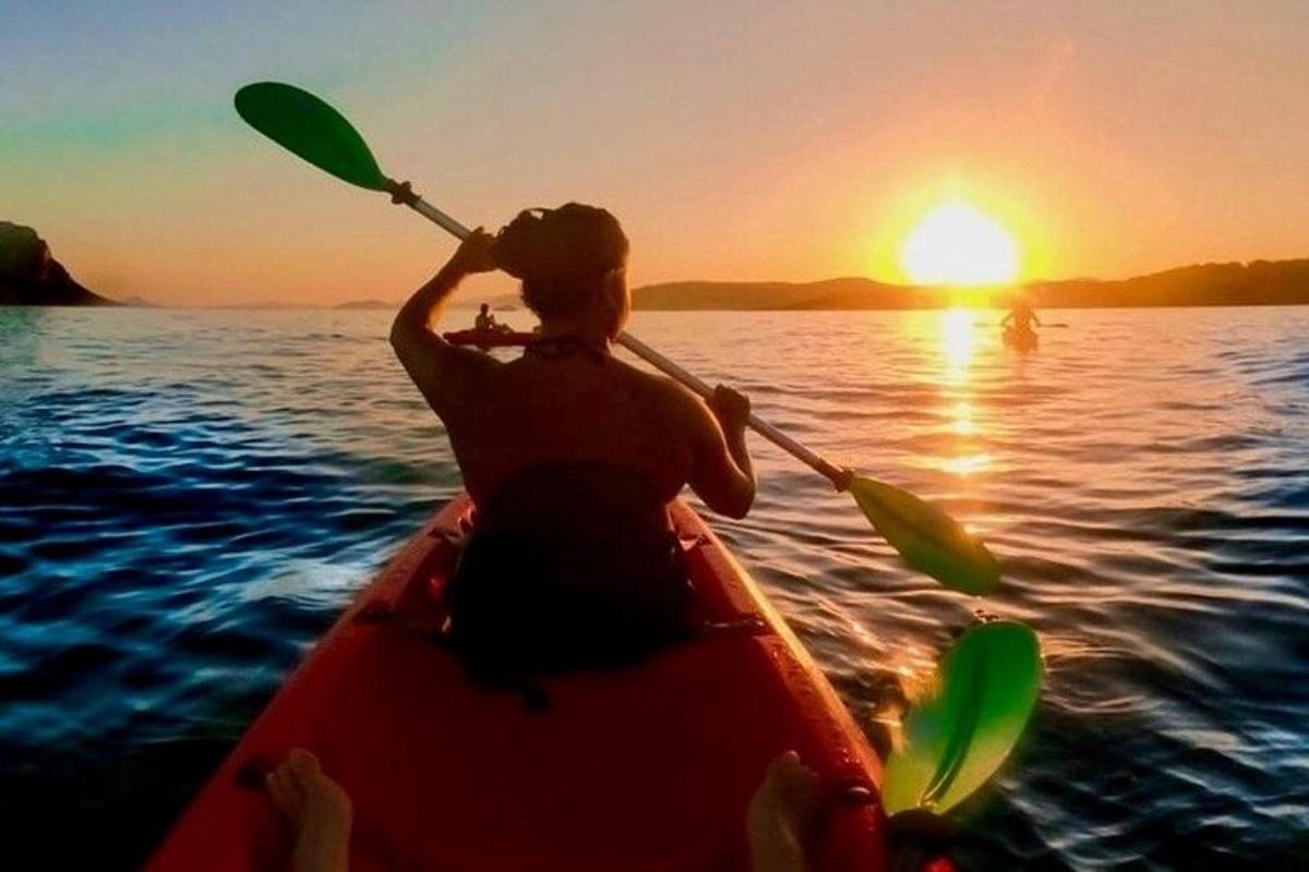 a woman in a kayak on the water at sunset